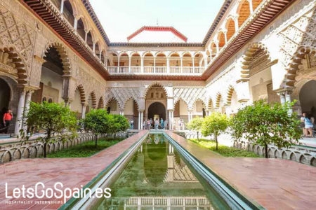 Courtyard of the Royal Alcázar of Seville with reflecting pool and Moorish arches in Spain